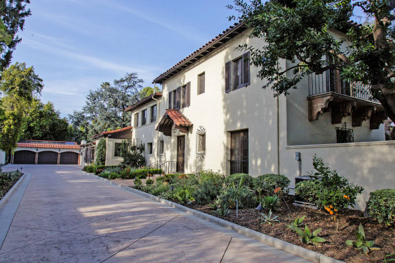 Front view of a charming blue house with a well-maintained lawn and brick pathway.