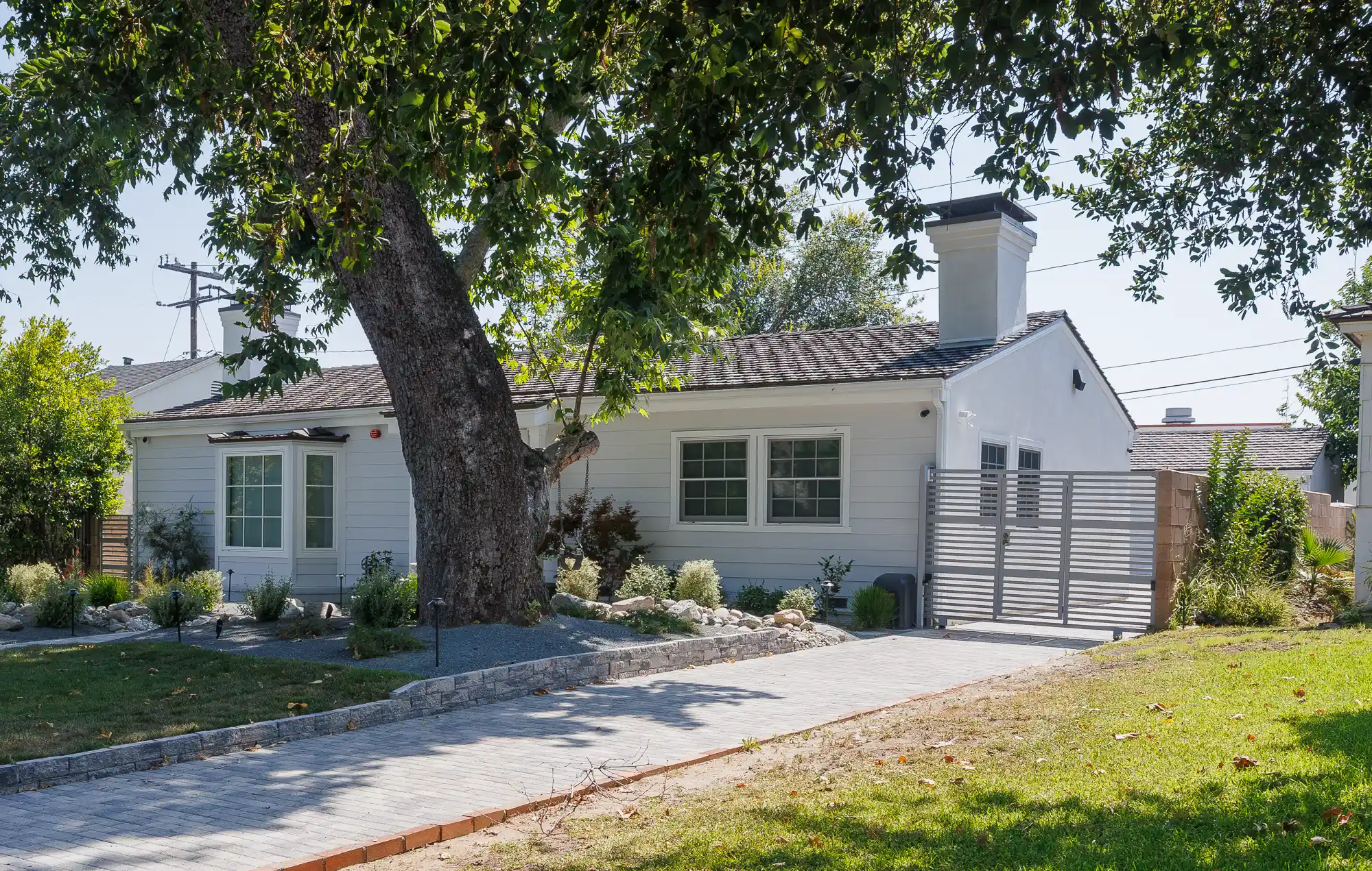 Front view of a charming blue house with a well-maintained lawn and brick pathway.